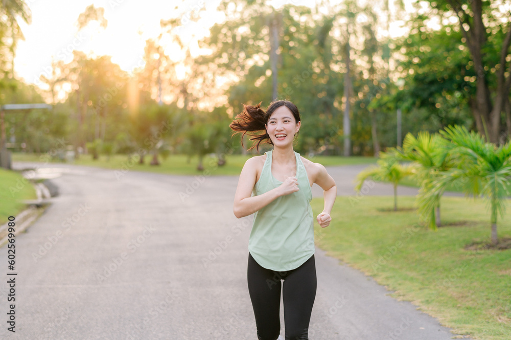 Fit Asian young woman jogging in park smiling happy running and enjoying a healthy outdoor lifestyle. Female jogger. Fitness runner girl in public park. healthy lifestyle and wellness being concept Fit Asian young woman jogging in park smiling happy running and enjoying a healthy outdoor lifestyle. Female jogger. Fitness runner girl in public park. healthy lifestyle and wellness being concept