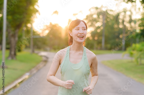 Fit Asian young woman jogging in park smiling happy running and enjoying a healthy outdoor lifestyle. Female jogger. Fitness runner girl in public park. healthy lifestyle and wellness being concept