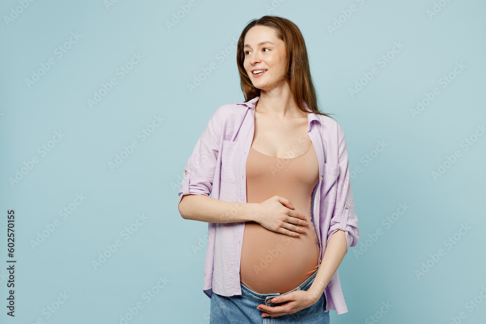 Side view young smiling fn pregnant future mom woman with belly tummy with baby wear casual clothes look aside on area isolated on plain pastel light blue cyan background. Maternity pregnancy concept. Side view young smiling fn pregnant future mom woman with belly tummy with baby wear casual clothes look aside on area isolated on plain pastel light blue cyan background. Maternity pregnancy concept.