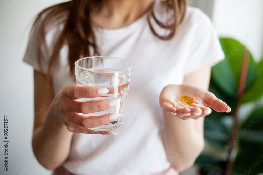 Beautiful woman holding capsule with a fish oil source of Omega-3 fatty acids Beautiful woman holding capsule with a fish oil source of Omega-3 fatty acids
