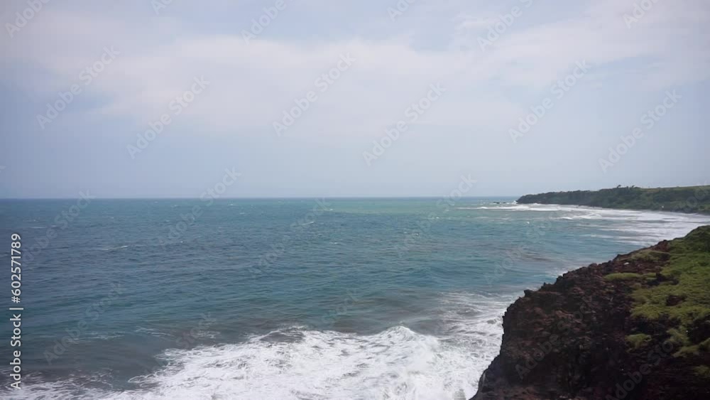 Beautiful view from the top of the cliff at the top of the cave, on the south coast of Garut, West Java, Indonesia, you can see a stretch of beach with blue sea water with big waves during the day Beautiful view from the top of the cliff at the top of the cave, on the south coast of Garut, West Java, Indonesia, you can see a stretch of beach with blue sea water with big waves during the day