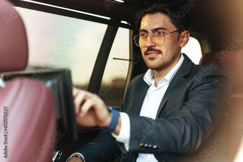 Young elegant businessman watching TV on the screen in luxury car © fotofabrika