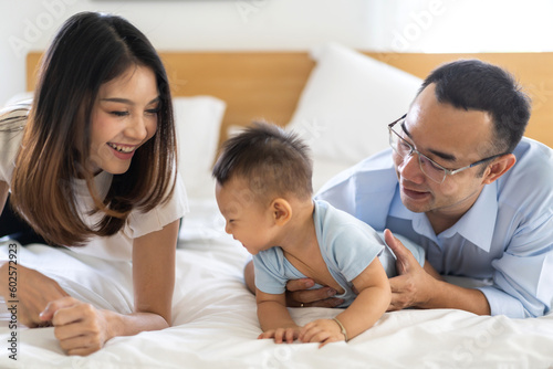 Portrait of enjoy happy love family asian father and mother playing with adorable little asian baby.newborn, infant.dad touching with cute son moments good time in a white bedroom.Love of family