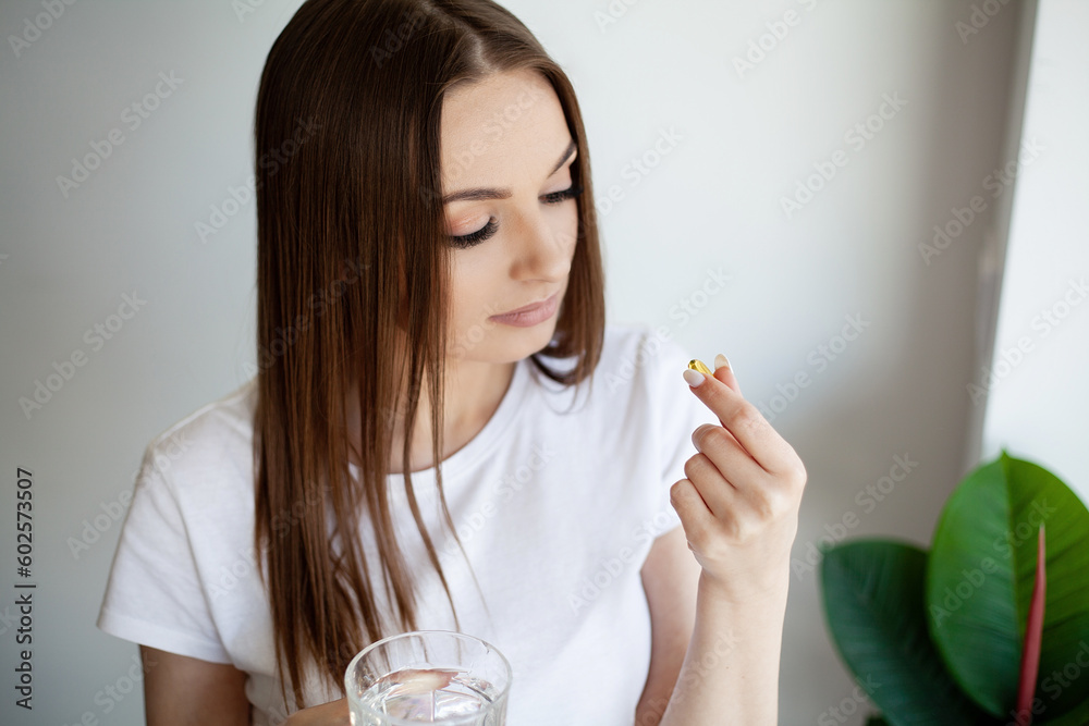 Beautiful woman holding capsule with a fish oil source of Omega-3 fatty acids Beautiful woman holding capsule with a fish oil source of Omega-3 fatty acids