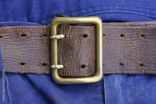 one old brown army leather belt with copper buckle in fabric blue trousers photo