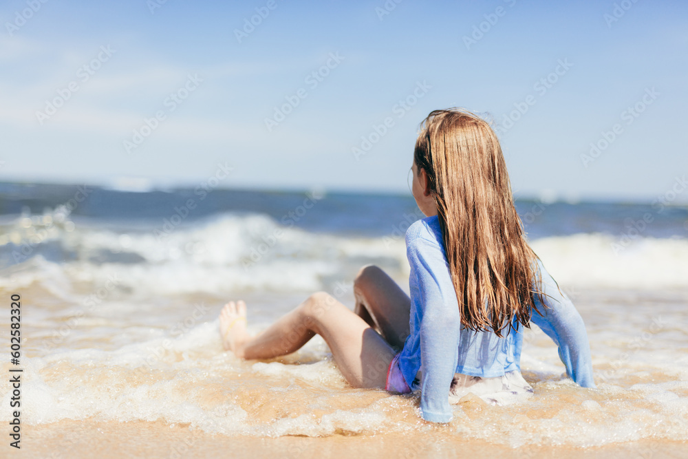 Fototapeta premium Young girl playing on the beach in waves at summer