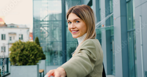Free Download Back view of woman in classic suit confidently walking the streets of the urban city and showing follow me gesture on camera. Follow me concept. - GFXLoad