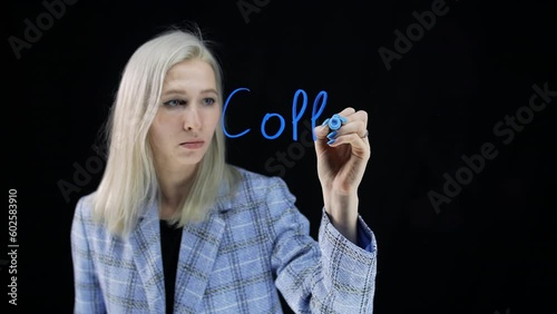 The word collators on a transparent board. A young girl writes words on the glass with a blue marker. photo