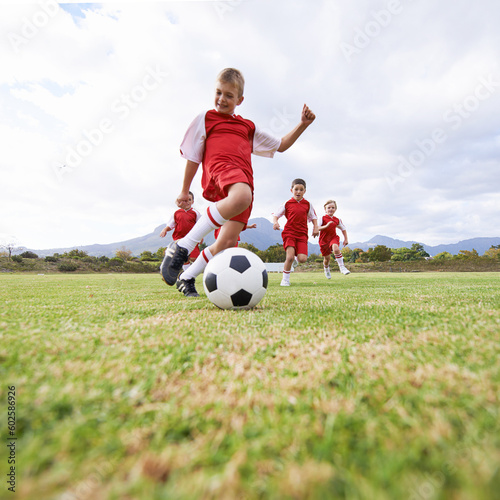 Running, kick and sports with children and soccer ball on field for training, competition and fitness. Game, summer and action with football player on pitch for goals, energy and athlete © Miko/peopleimages.com