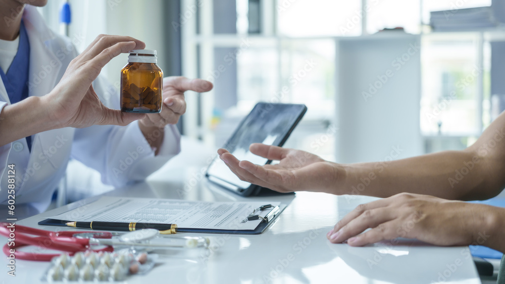 Male doctor is consulting with a young man about prostate cancer and venereal disease and sexual dysfunction about the causes of erectile dysfunction in an examination room. Male doctor is consulting with a young man about prostate cancer and venereal disease and sexual dysfunction about the causes of erectile dysfunction in an examination room.