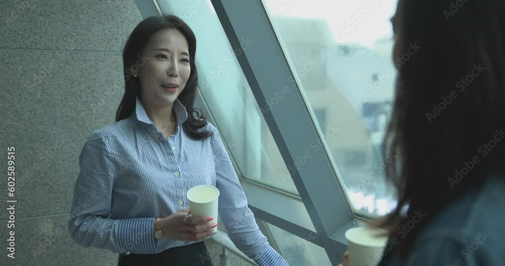 동료 직원과 대화하며 미소를 짓고있는 블루셔츠를 입은 여성 동료 직원과 대화하며 미소를 짓고있는 블루셔츠를 입은 여성