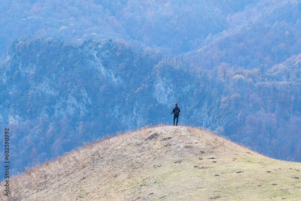 A tourist (hiker) standing on a hill looks into the distance on sunny autumn day. Dilijan National Park, Tavush Province, Armenia.