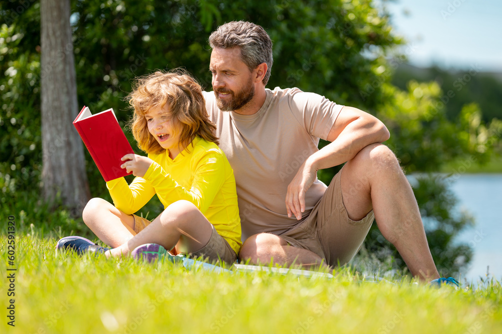 Father and son reading book in park, man encourages boy to knowledge, family education. Father and child read book together outdoor. Happy parent reading with child book on summer nature in park. Father and son reading book in park, man encourages boy to knowledge, family education. Father and child read book together outdoor. Happy parent reading with child book on summer nature in park.