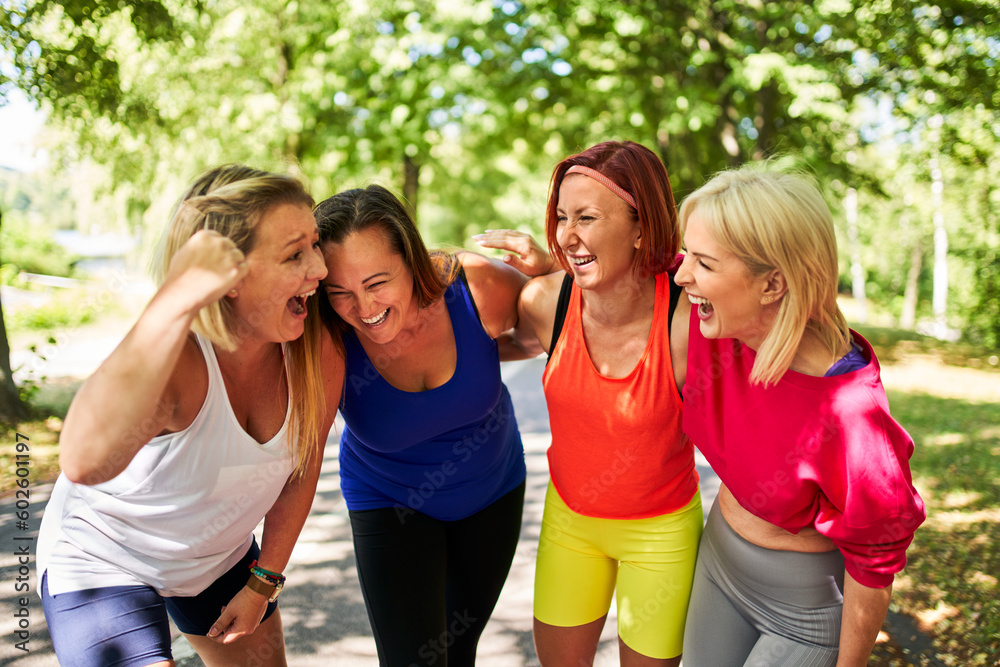 Female friends having fun laughing after outdoors exercise class in park during summer Female friends having fun laughing after outdoors exercise class in park during summer