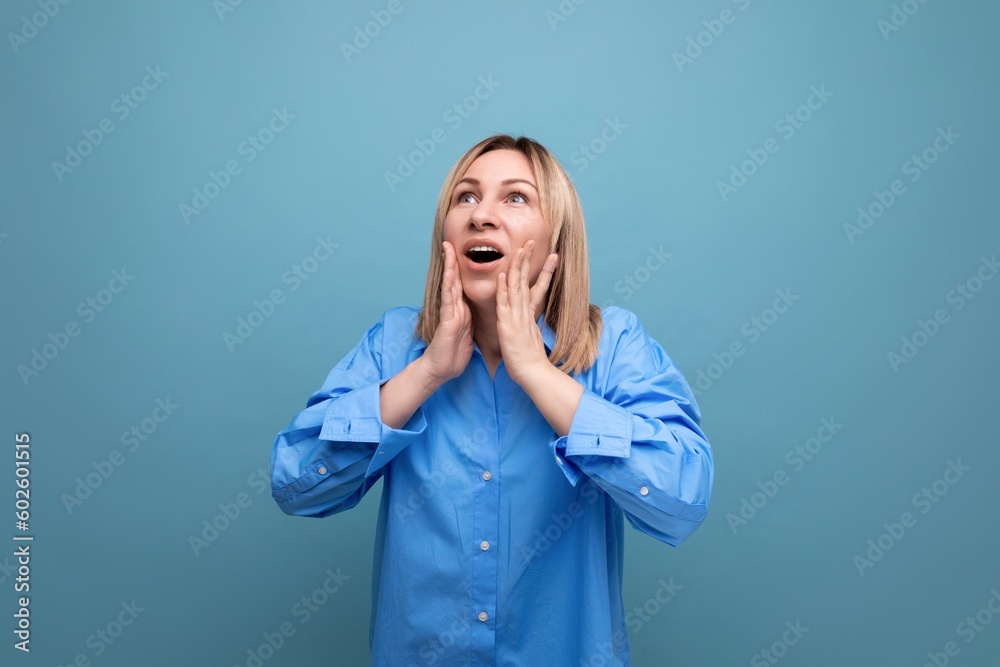 shocked young woman in casual look grabbing her head on blue background shocked young woman in casual look grabbing her head on blue background