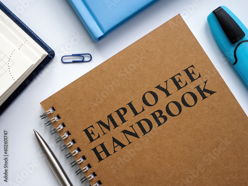 An Employee handbook near notepads and pen. photo
