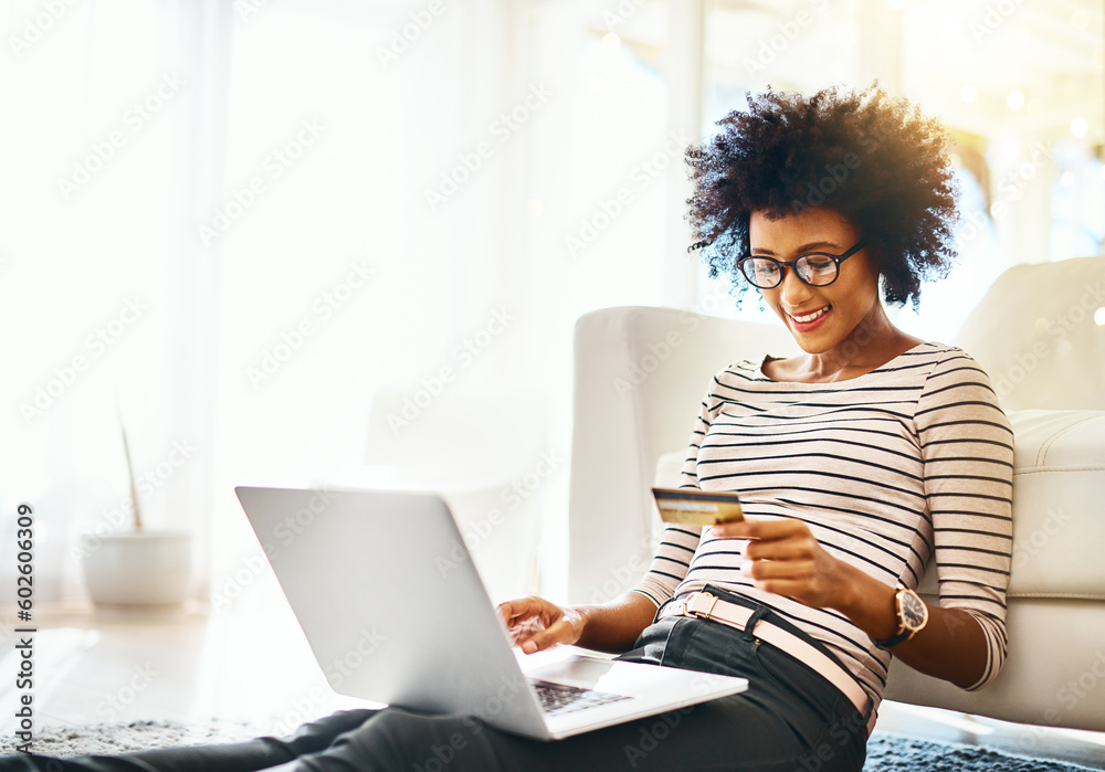 Young woman, laptop and credit card while doing online shopping sitting on ground. Home, happiness and computer internet deal of African female person on an ecommerce app reading banking details Young woman, laptop and credit card while doing online shopping sitting on ground. Home, happiness and computer internet deal of African female person on an ecommerce app reading banking details