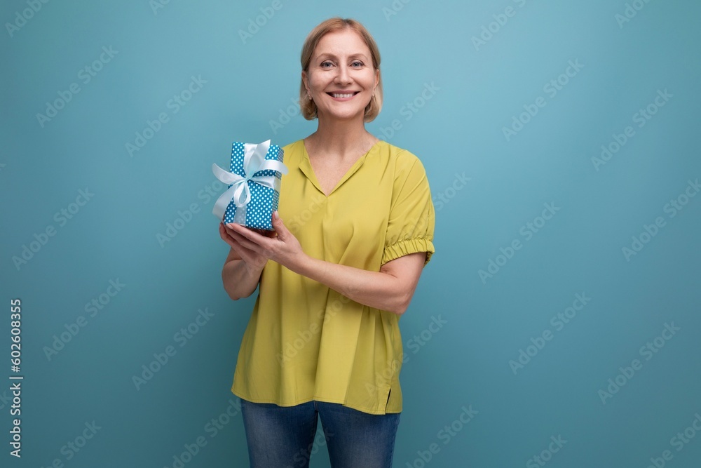 happy blonde middle aged woman with gift on studio background with copy space happy blonde middle aged woman with gift on studio background with copy space