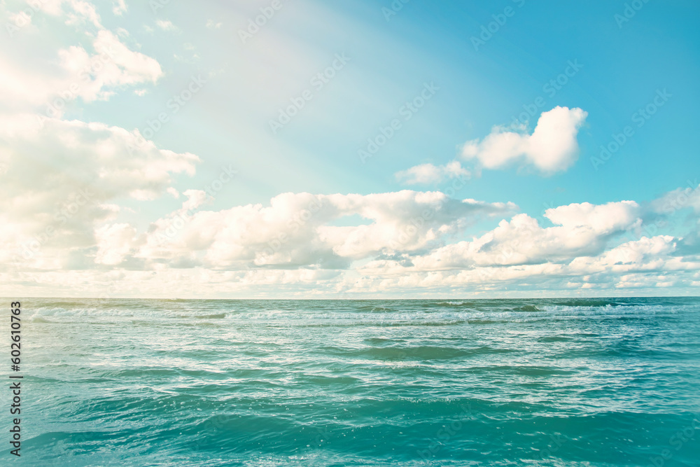 Obraz premium Panorama of a calm sea with clouds on the horizon. Background on the theme of summer vacation and ecology. Crystal clear ocean water.