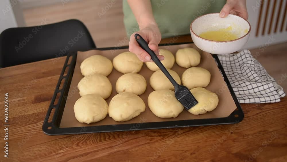A girl makes buns. Cooking sweet pastries. Shaping buns on a baking tray A girl makes buns. Cooking sweet pastries. Shaping buns on a baking tray