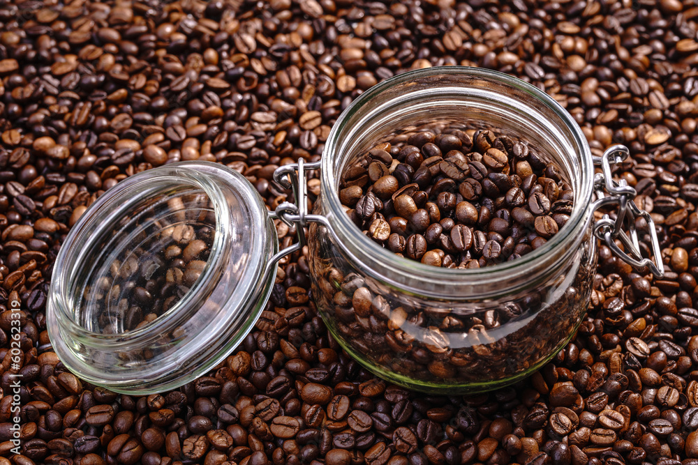 Palone ziarna kawy wypełniające tło i przewrócony słoik