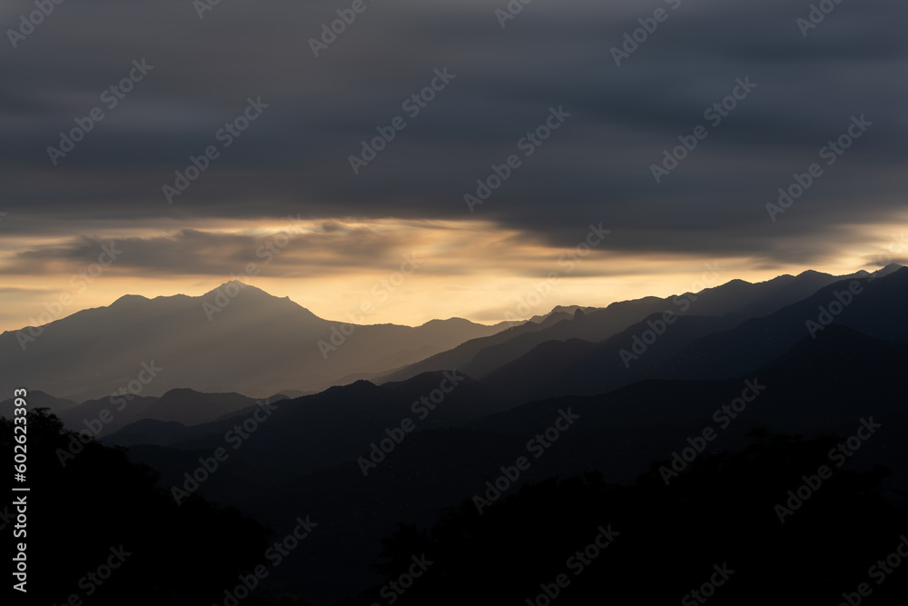 Layers of Mountains at Sunset with Silhouette and Dramatic Clouds