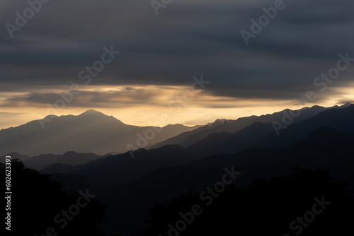 Layers of Mountains at Sunset with Silhouette and Dramatic Clouds
