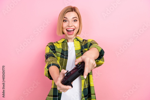 Portrait of impressed cheerful lady arms hold controller enjoy video game isolated on pink color background