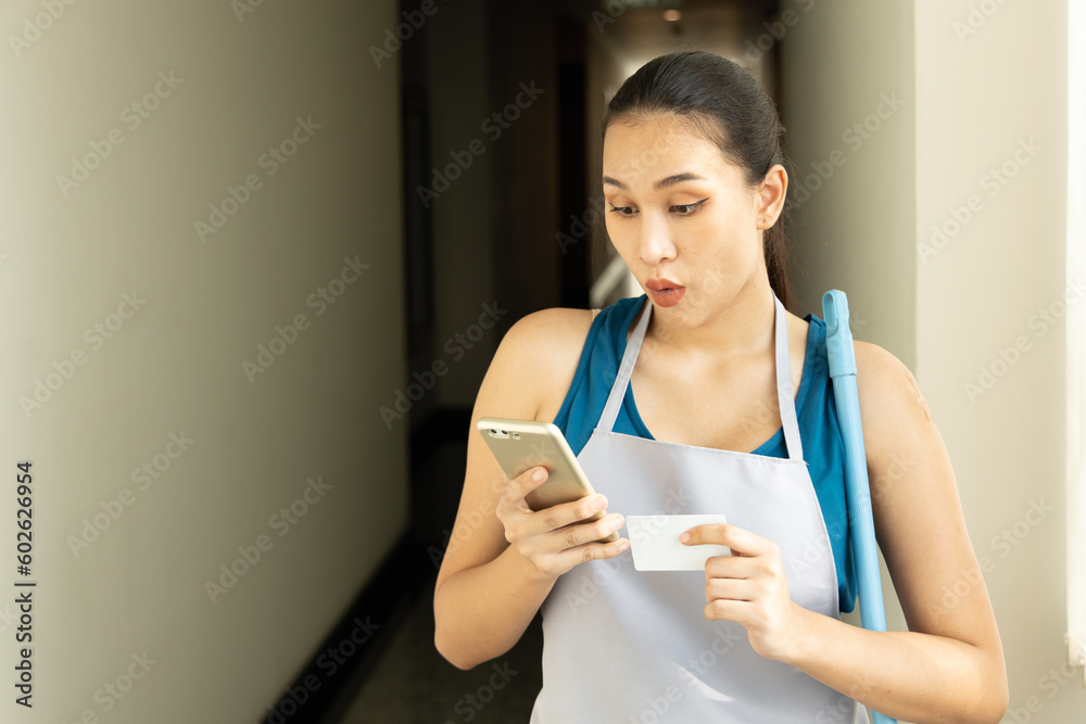 Excited positive Asian cleaning service worker woman, using smartphone with good connection Excited positive Asian cleaning service worker woman, using smartphone with good connection