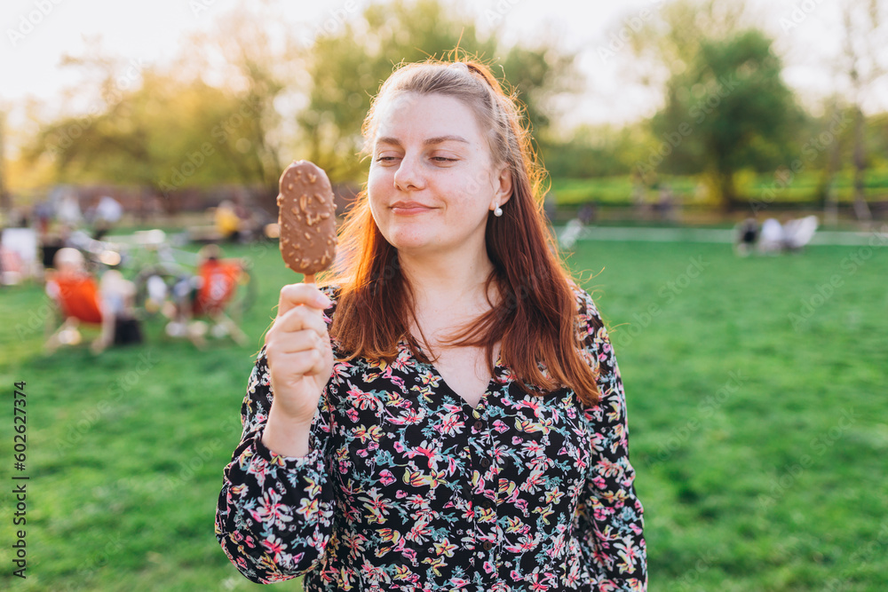 Happy young woman with delicious chocolate ice cream outdoors. Unhealhty food and weight loss concept. Summer time, eating Happy young woman with delicious chocolate ice cream outdoors. Unhealhty food and weight loss concept. Summer time, eating