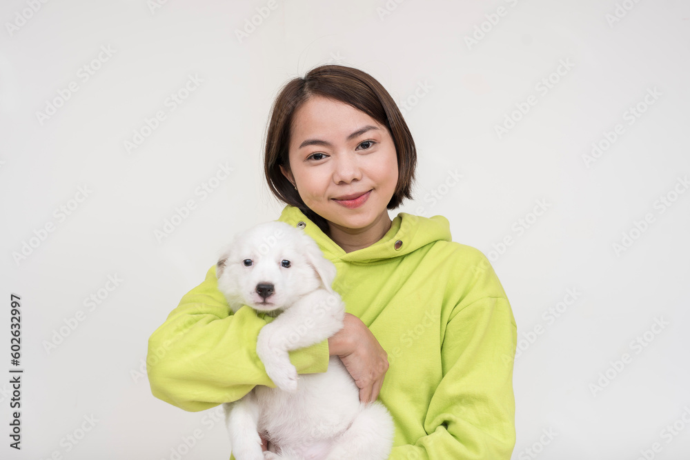 A young and gentle pet owner posing while holding her white dog, puppy. Isolated on a white background. A young and gentle pet owner posing while holding her white dog, puppy. Isolated on a white background.