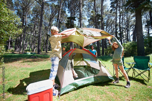 Children, tent and team camping in forest for shelter, cover or insurance together on the grass in nature. Happy kids in teamwork setting up tents for camp adventure or holiday vacation in the woods