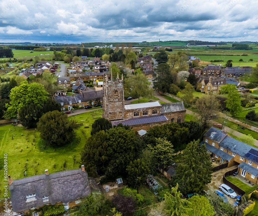 An aerial view north east over the church and village of Chipping Warden, UK in summertime