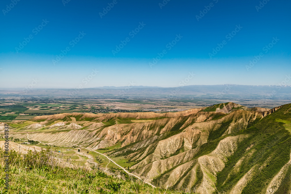 Naklejka premium Road in a mountain valley. Clay mountain hills.