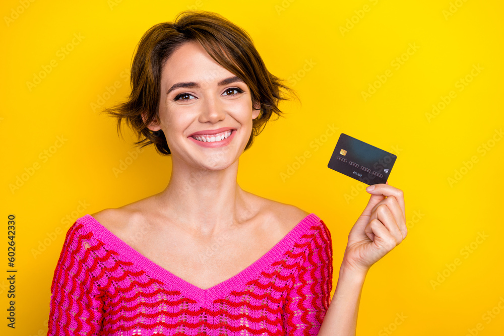 Portrait of beautiful young girl wear pink knitted shirt hold plastic shopping card advert cashback service ad isolated on yellow color background