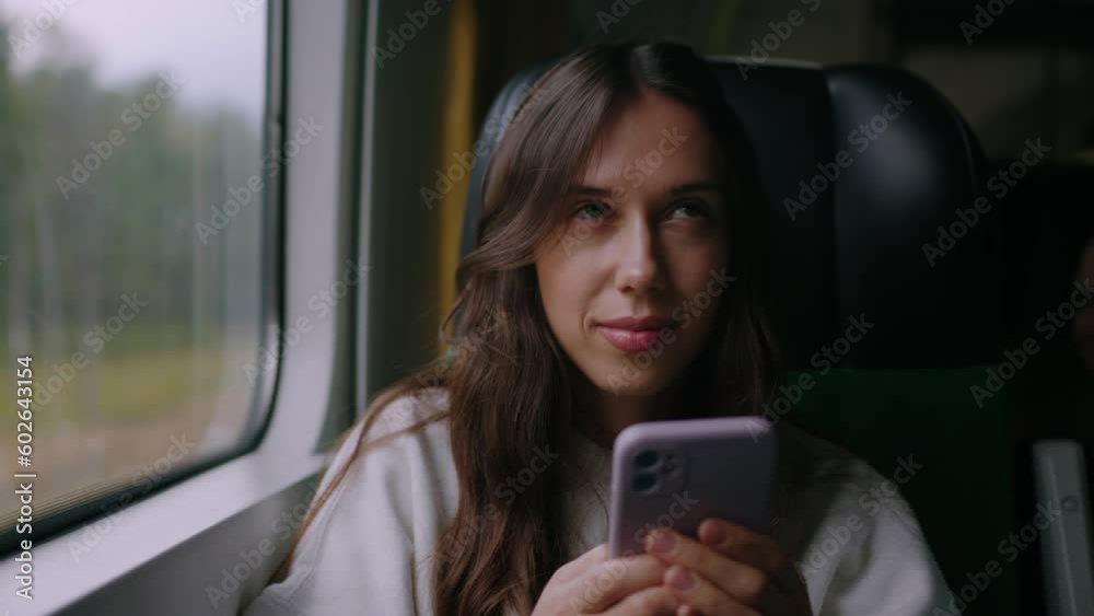 A young woman is texting with colleagues on a mobile phone. Traveling on a modern train