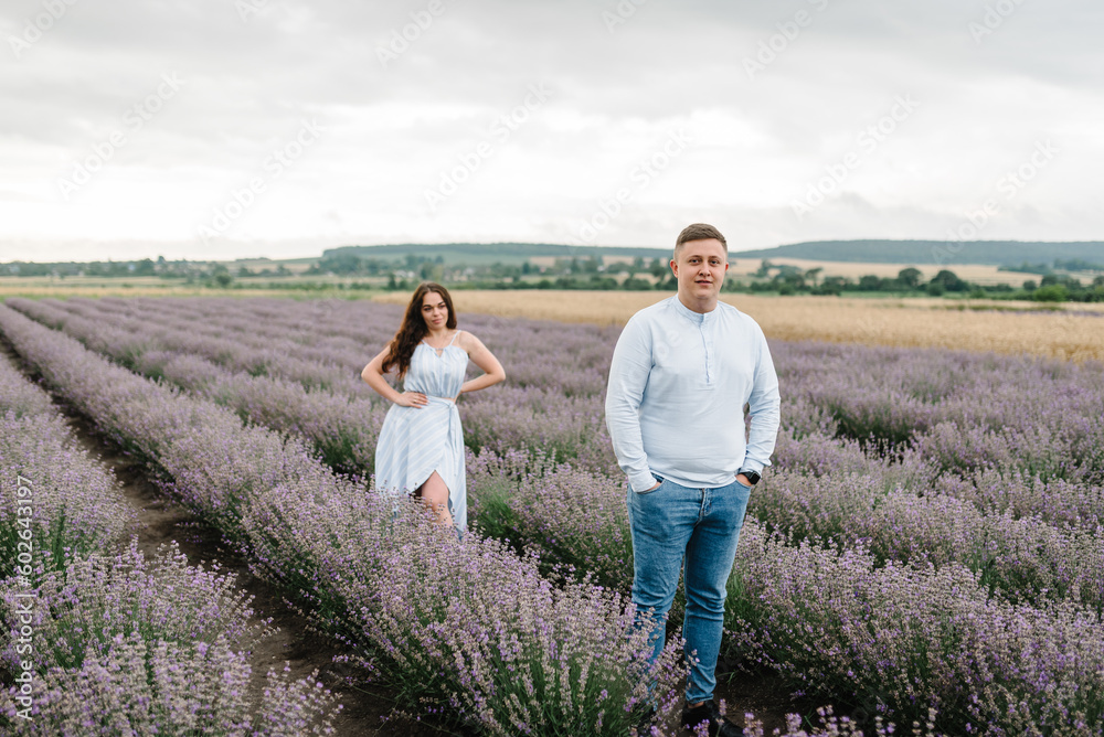 Couple in violet lavender field of flowers. Man and woman standing and enjoys floral glade, summer nature. Loving family walking at sunset. France, Provence. Honeymoon trip, traveling. Closeup Couple in violet lavender field of flowers. Man and woman standing and enjoys floral glade, summer nature. Loving family walking at sunset. France, Provence. Honeymoon trip, traveling. Closeup