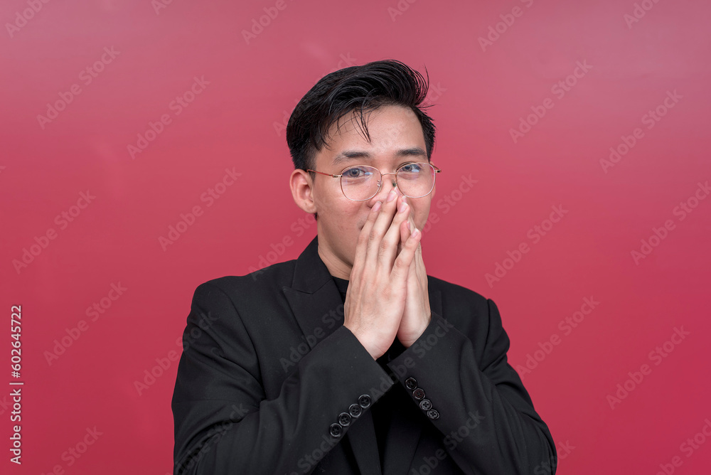 Portrait of a shocked young man wearing glasses with both hands on his mouth. Isolated on a red background. Portrait of a shocked young man wearing glasses with both hands on his mouth. Isolated on a red background.