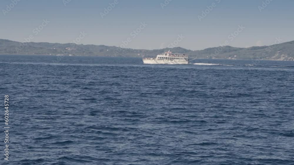 Tourist boat sailing along tropical island Corfu in Greece transporting tourists to famous caves on Paxos island Tourist boat sailing along tropical island Corfu in Greece transporting tourists to famous caves on Paxos island