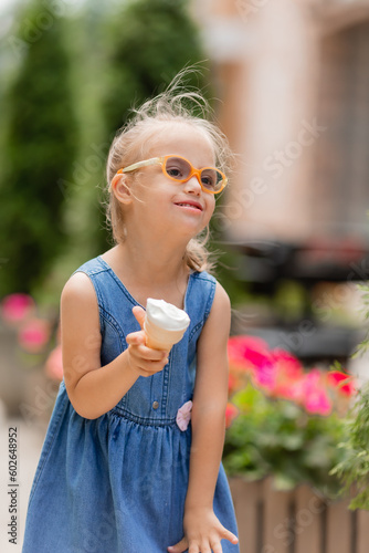 a little happy girl with down syndrome eats ice cream in the summer on a walk © КРИСТИНА Игумнова
