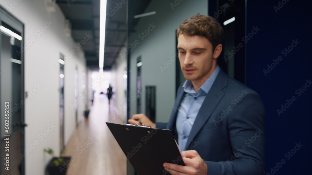 Happy worker checking papers on clipboard. Office mentor making notes walking Happy worker checking papers on clipboard. Office mentor making notes walking