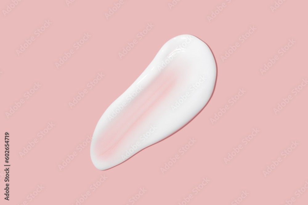 Fototapeta premium A dab of cosmetic cream. Light, smooth surface. Texture of spreadable cream. Liquid cream smear. On a pink background.