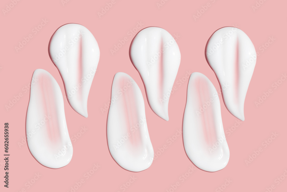 Lots of smears of cosmetic cream. Light, smooth surface. Texture of spreadable cream. Liquid creamy strokes. On a pink background. Cosmetic background, banner. Lots of smears of cosmetic cream. Light, smooth surface. Texture of spreadable cream. Liquid creamy strokes. On a pink background. Cosmetic background, banner.
