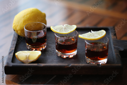 Obraz na płótnie three shot glasses with lemon slices on a wooden plate w salonie