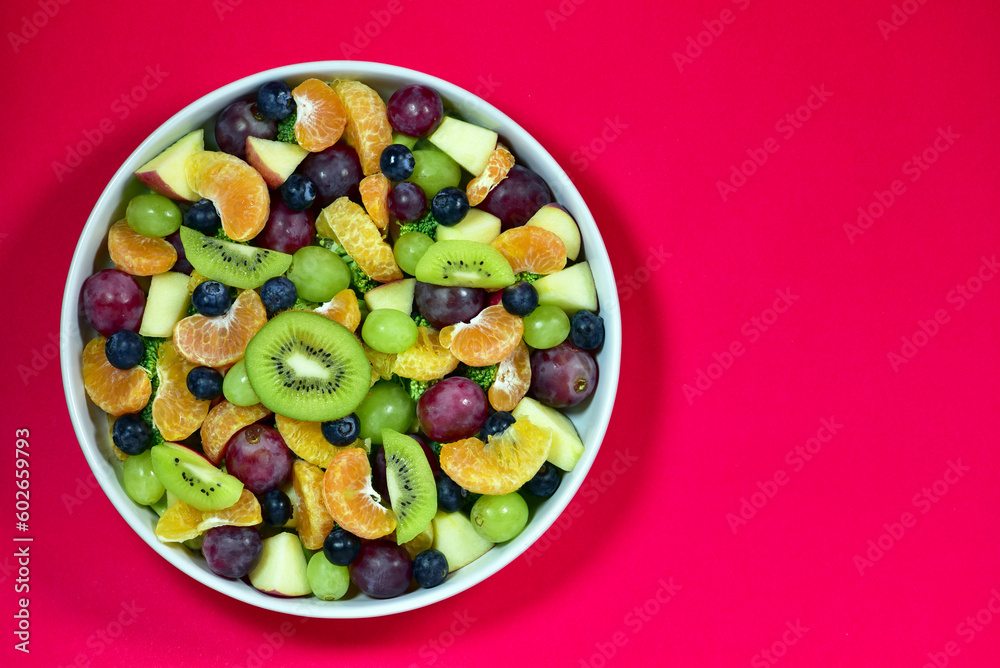 Healthy fresh fruit salad bowl on red background. Top view. Healthy food concept, healthy high vitamin fruit, mixed fruit background. Healthy fresh fruit salad bowl on red background. Top view. Healthy food concept, healthy high vitamin fruit, mixed fruit background.