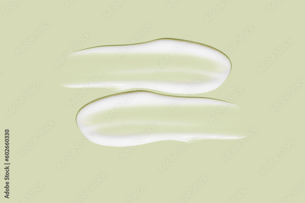 Lots of smears of cosmetic cream. Light, smooth surface. In a row. At an angle. Top view. Texture of flowing cream. Liquid creamy strokes. On green background. Cosmetic background, banner. Lots of smears of cosmetic cream. Light, smooth surface. In a row. At an angle. Top view. Texture of flowing cream. Liquid creamy strokes. On green background. Cosmetic background, banner.