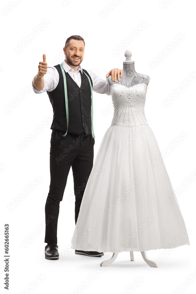 Tailor standing next to a bridal gown on a doll mannequin and gesturing thumbs up Tailor standing next to a bridal gown on a doll mannequin and gesturing thumbs up