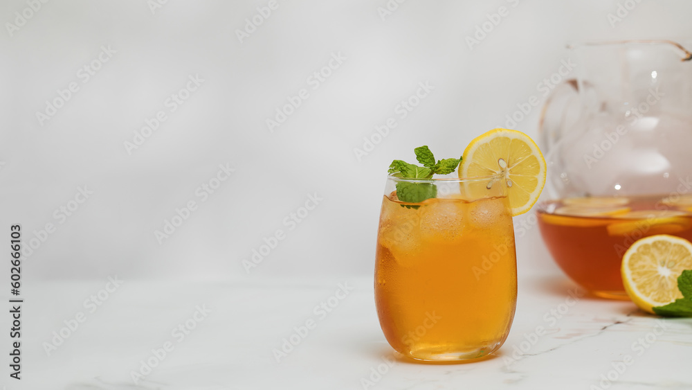 A glass of cold tea, ice cubes, lemon slices and a sprig of mint. Cooling summer drinks. A glass of cold tea, ice cubes, lemon slices and a sprig of mint. Cooling summer drinks.
