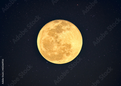 Yellow full moon with crater textured glowing with starry in night sky