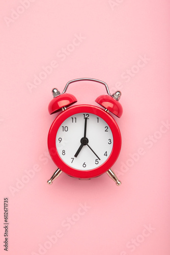 Red vintage alarm clock on pink background. Space for text